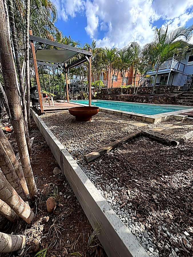 Timber-edged garden bed retaining wall beside a pool