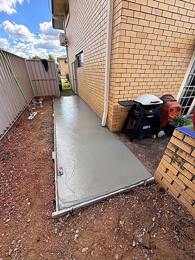 Finished small concrete pad beside a brick house